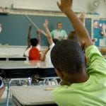 Children raising hands in a classroom setting