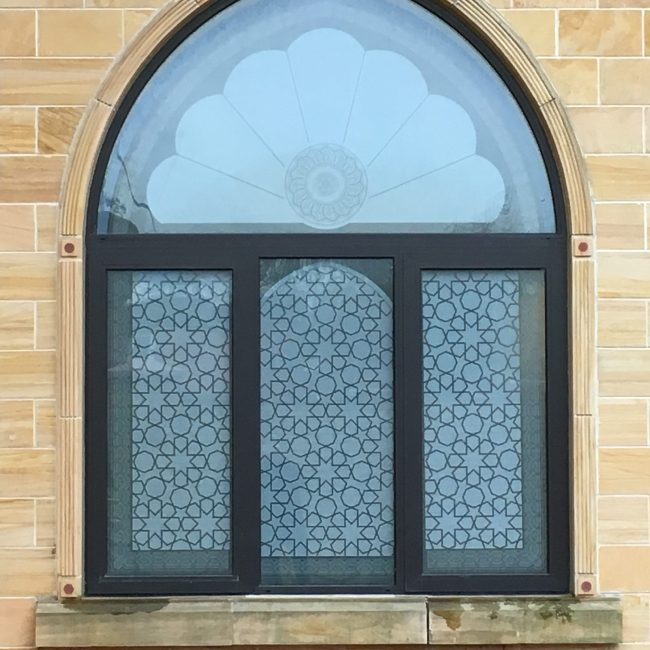 an external window with an arched top featuring patterned window film