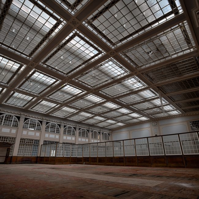 The inside of a former factory that has lots of glass on both the walls and ceiling