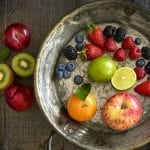 Bowl of fruit that includes apples, oranges, strawberries, limes, kiwis and blueberries.